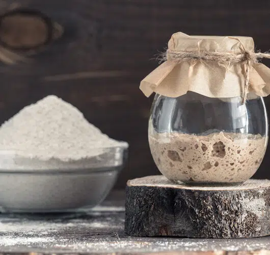 Sauerteig Starter im Glas mit Bläschen und Volumenanstieg.